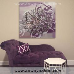 a purple couch sitting in front of a painting on the wall next to a white table