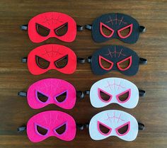 six masks with different designs on them sitting on top of a wooden table next to each other