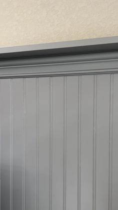 a cat sitting on top of a wooden shelf next to a wall with striped walls