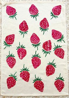 a white table cloth with red strawberries on the front and green leaves on the back