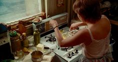 a woman is cooking in the kitchen with her hands on the stove top and holding a knife