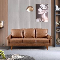 a brown leather couch sitting in a living room next to a book shelf