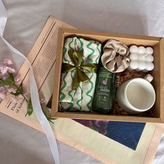 an open box containing soaps, candles and other items on a white tablecloth