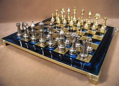 a metal chess set sitting on top of a blue and gold tablecloth with silver pieces