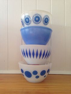 a stack of blue and white bowls sitting on top of a wooden table next to a wall