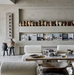 a living room filled with lots of furniture and vases on the wall above it