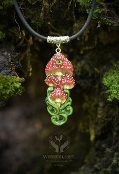 a green and red mushroom necklace hanging from a leather cord