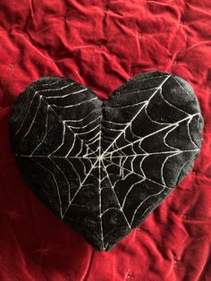 a heart shaped rock with a spiderweave pattern on it's side sitting on a red blanket