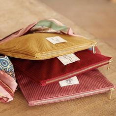 three zippered pouches sitting on top of a wooden table next to each other