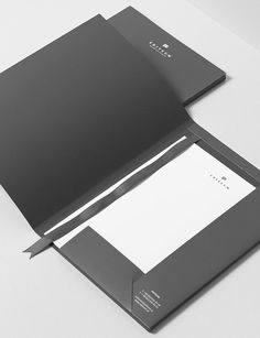 an open black folder with white paper on the top and bottom, sitting on a table