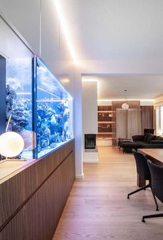 a fish tank in the middle of a room with chairs and tables around it,