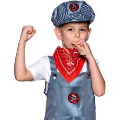 a young boy wearing an apron and hat eating something with his fist up in the air