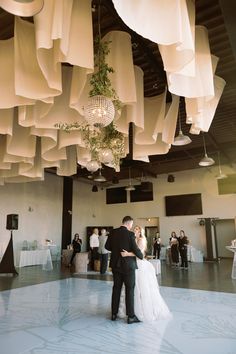 a bride and groom standing in front of a chandelier at their wedding reception