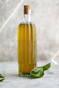 a glass bottle filled with liquid next to green leaves