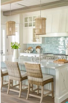 a kitchen with an island and chairs in the center, along with two lamps hanging from the ceiling