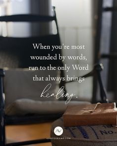 a book sitting on top of a wooden table next to a chair and a quote that says, when you're most wounded by words, run to the only word that always brings