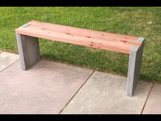 a wooden bench sitting on top of a cement slab next to green grass in a park