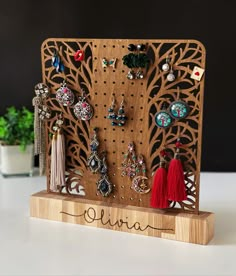 a wooden holder with earrings and tassels hanging from it's sides on a table