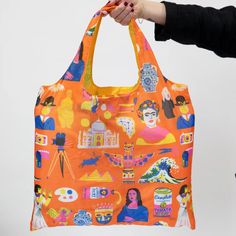 a woman holding an orange handbag with colorful images on the front and sides,