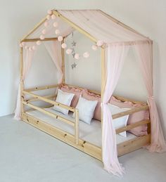 a wooden bed with pink curtains and pillows