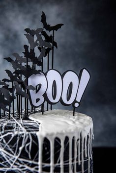 a birthday cake decorated with black and white icing, bats and the word boo on top