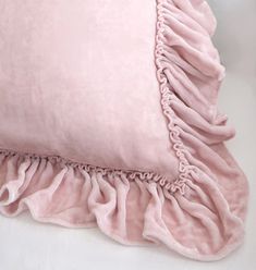 a pink pillow with ruffled edges on a white surface