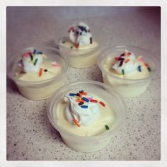 four small plastic containers filled with whipped cream and sprinkles