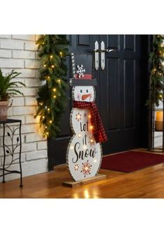 a lighted snowman standing in front of a door