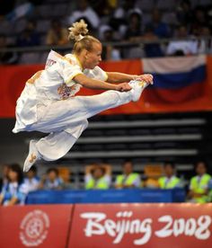 a woman in white doing a trick on a trampoline at an indoor event