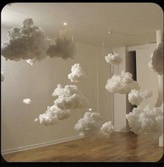 there are clouds floating in the air over a room with wood flooring and white walls