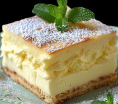 a piece of cake on a plate with mint sprig and powdered sugar