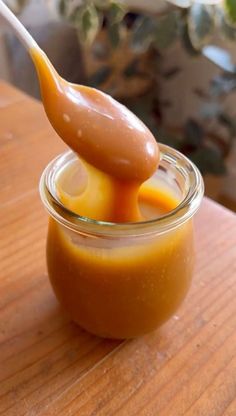 a spoon full of caramel sauce on top of a wooden table