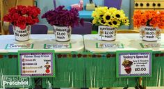 three buckets filled with flowers sitting on top of a table in front of chairs