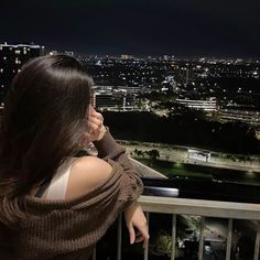 a woman is looking out over the city at night