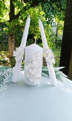 a white candle sitting on top of a table covered in frosted flowers and ribbons