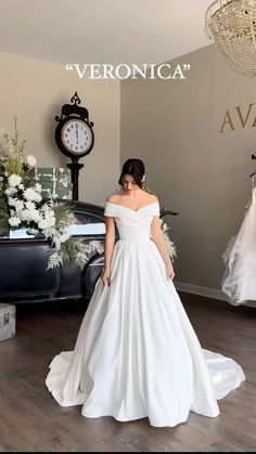 a woman in a white wedding dress standing next to a black car