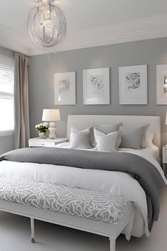 a white and gray bedroom with pictures on the wall above the bed, along with two nightstands