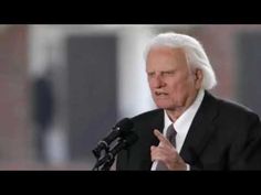 an older man giving a speech in front of a microphone