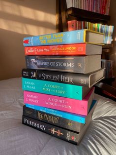 a stack of books sitting on top of a bed