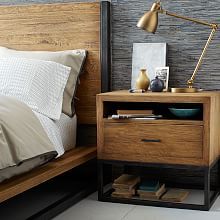 a bed with a wooden headboard and night stand next to a nightstand that has books on it