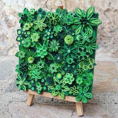 an art piece made out of green paper with flowers on the front and back sides