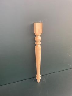 a wooden candle holder sitting on top of a gray table next to a white wall