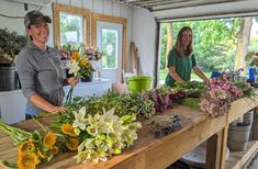 two women standing behind a table with flowers on it