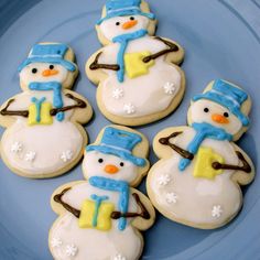 frosted cookies decorated like snowmen on a blue plate