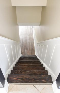 the stairs are made of wood and have white painted walls, along with marble flooring