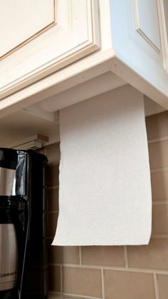 a roll of toilet paper is hanging on the wall above a black coffee pot and microwave