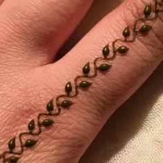 a woman's hand with an intricate design on it, showing the ring finger