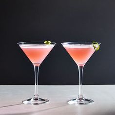 two martinis with lime garnish sit on a table