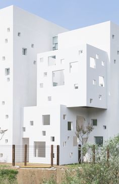 a white building with many windows on the front and back sides, surrounded by trees