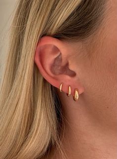 a woman's ear with two small gold hoops